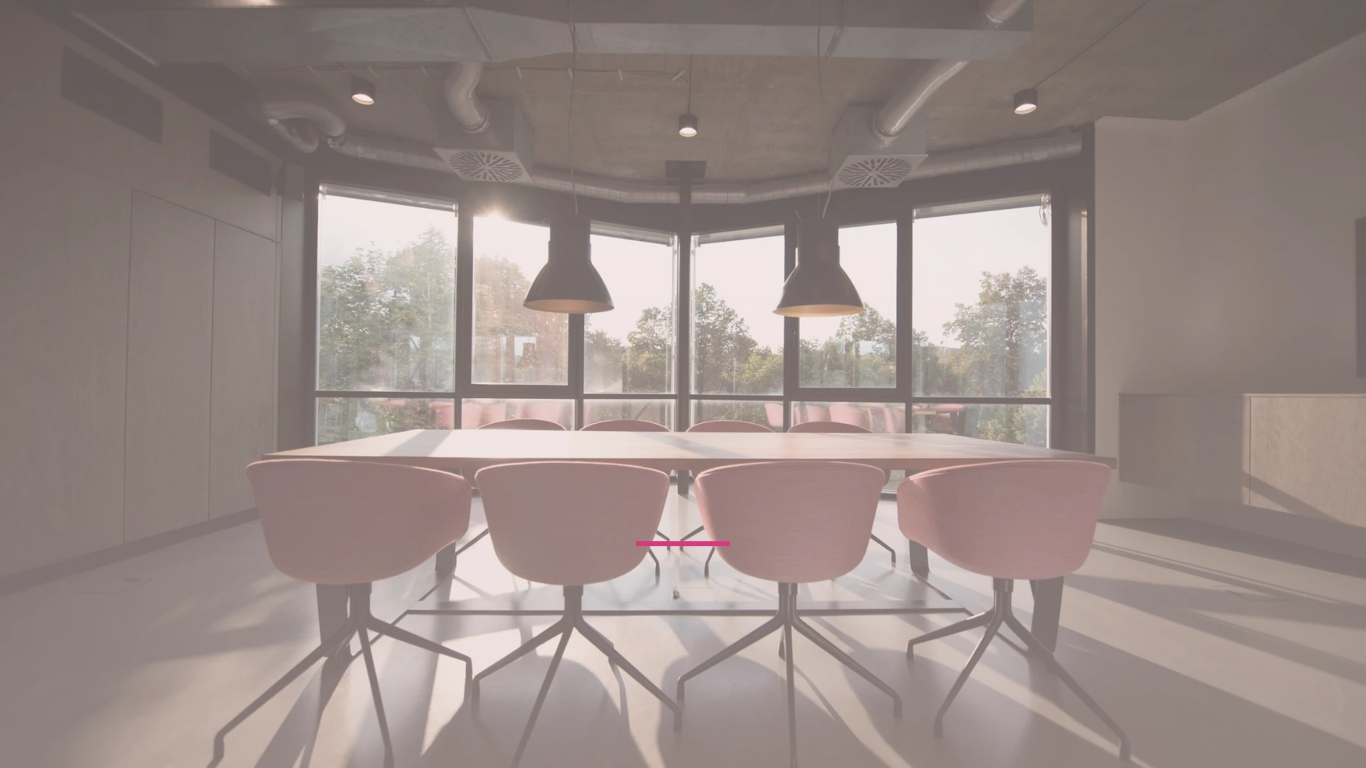Sala de reuniones vacía con sillas rosas en empresa, representando la desalineación de equipos directivos