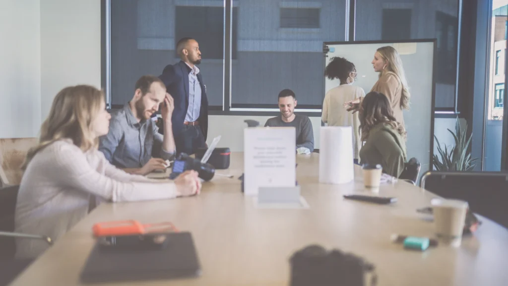 Sala de reuniones con varias conversaciones paralelas y sin conexión real, reflejo de un equipo que trabaja junto, pero sin estar alineado en su comunicación
