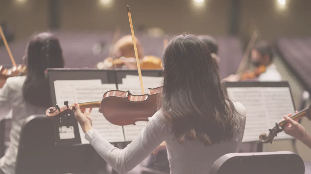 Violinista de una orquesta tocando coordinada con el resto del conjunto, equipo que funciona de forma integrada