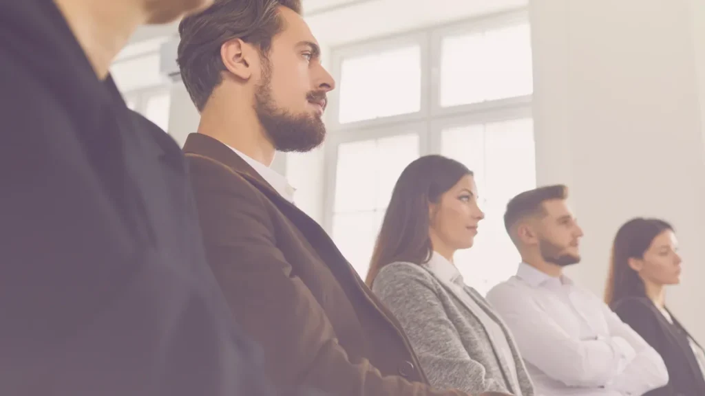 Fila de profesionales escuchando con atención en una reunión de empresa, reflejo del equipo que percibe si el compromiso con las personas es real